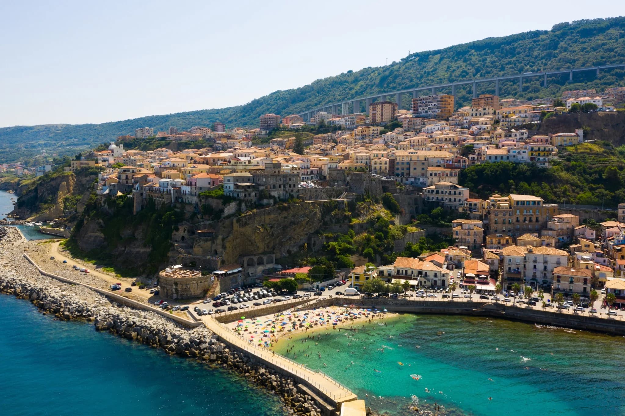 Veduta aerea di Pizzo: le case del centro sul promontorio a picco sul mare, una spiaggia con ombrelloni e il molo